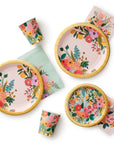 Set of floral-patterned plates, cups, and napkins on a white background