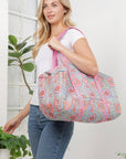Woman holding a large, patterned bag in a home setting with plants.