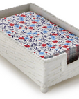 A white woven-texture rectangular tray or basket with a floral-patterned insert featuring red, blue, and navy flowers on a white background, shown on a light gray studio background.