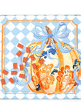 A Mahjong mat featuring a decorative autumn illustration. The design shows a large orange watercolor pumpkin with blue floral details and a blue ribbon bow, set against a light blue and white checkered background with an orange border.