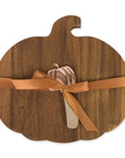 A pumpkin-shaped wooden serving board with a warm brown wood grain finish, wrapped with a tan ribbon and bow, and a small decorative pumpkin topper, shown on a plain white background.