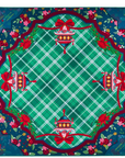 A Mahjong mat featuring a festive Christmas design with a green plaid center, red bows, poinsettias, and ornate holiday ornaments, surrounded by a dark blue floral border.