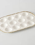 White ceramic egg tray with gold rim on a light gray background