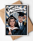 Graduation-themed card with a couple in caps and gowns, text 'Congrats on the World's Most Expensive Hat', and a brown envelope.