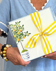 A person holding a clear cellophane bag with a lemon tree design and a yellow ribbon.