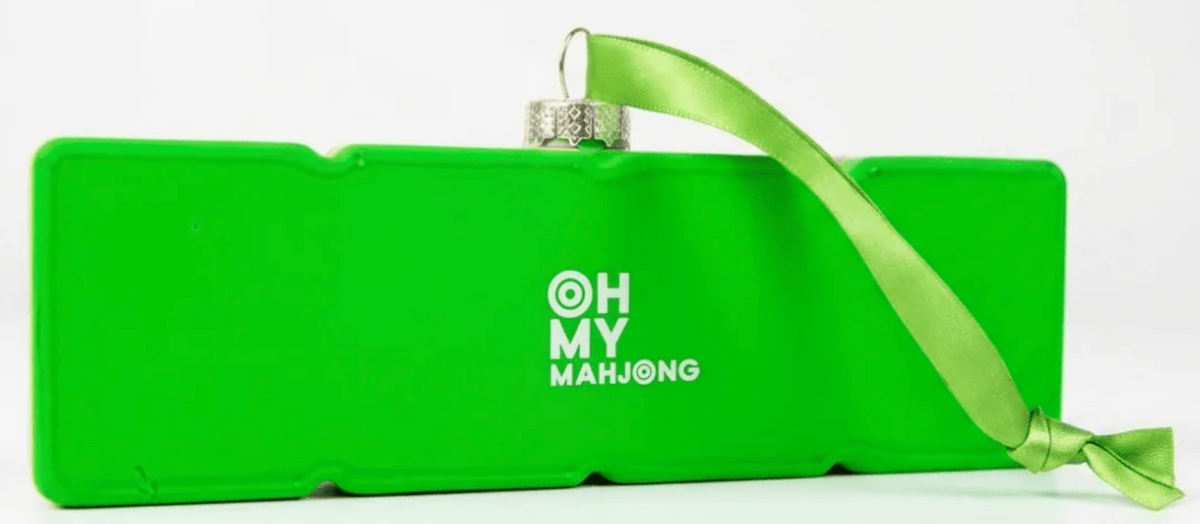 A bright green rectangular ornament with a hanging ribbon and a silver ball finial, featuring the white text 'OH MY MAHJONG' on the front, set against a plain white background.