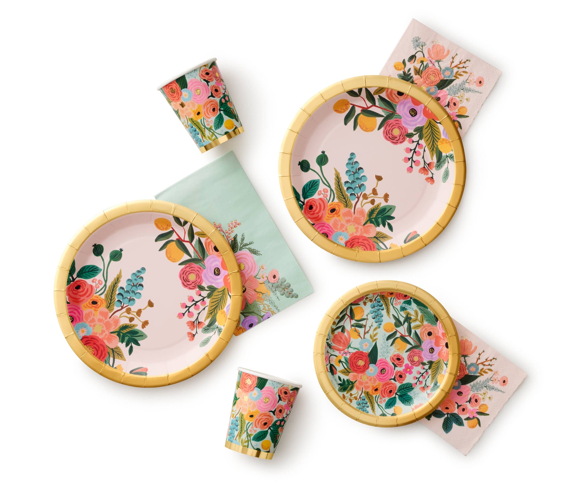 Set of floral-patterned plates, cups, and napkins on a white background