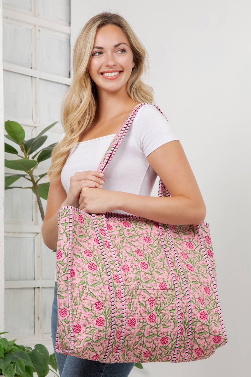 Woman holding a pink floral bag against a white wall