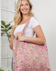 Woman holding a pink floral bag against a white wall