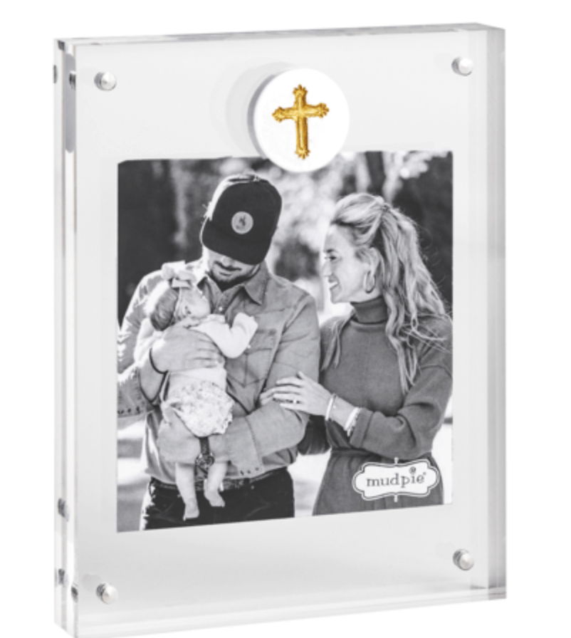 Clear photo frame with a black and white photo of a couple holding a baby, a gold cross, and 'mudpie' branding.