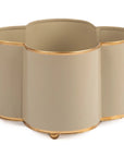 A beige cachepot with gold trim detail feet, designed in a quatrefoil shape with four round openings for plant pots.