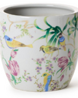 A white ceramic planter pot decorated with a delicate hand-painted style illustration of birds, flowers, and leaves in green, pink, yellow, and blue.