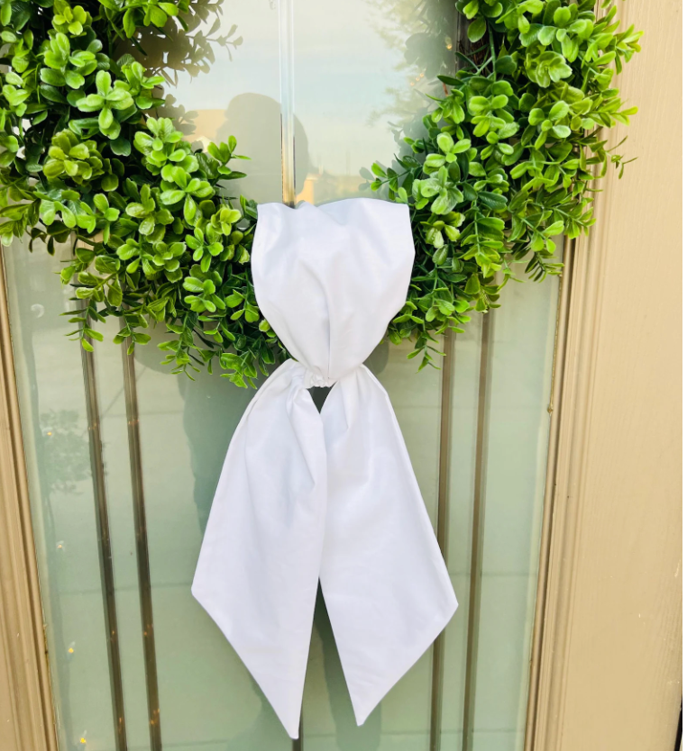 Green wreath with a white bow on a door
