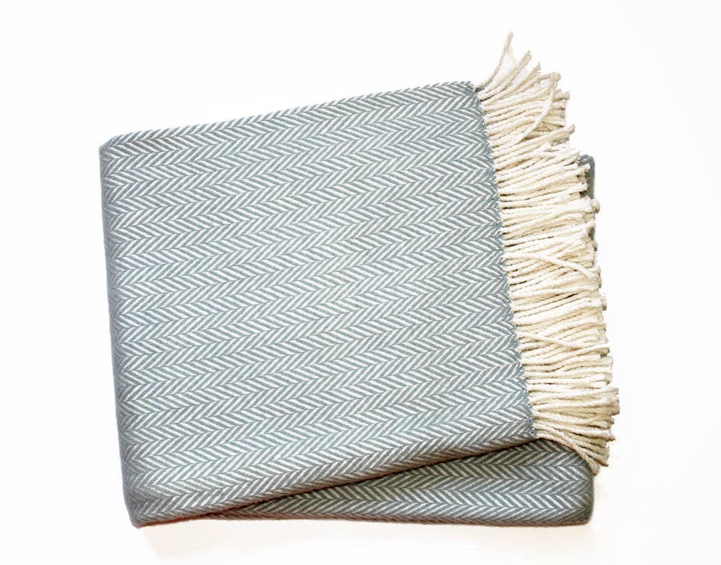 Folded blanket with chevron pattern and fringed edge on a white background