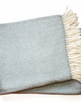 Folded blanket with chevron pattern and fringed edge on a white background