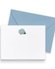 White card with floral design and blue envelope on a white background