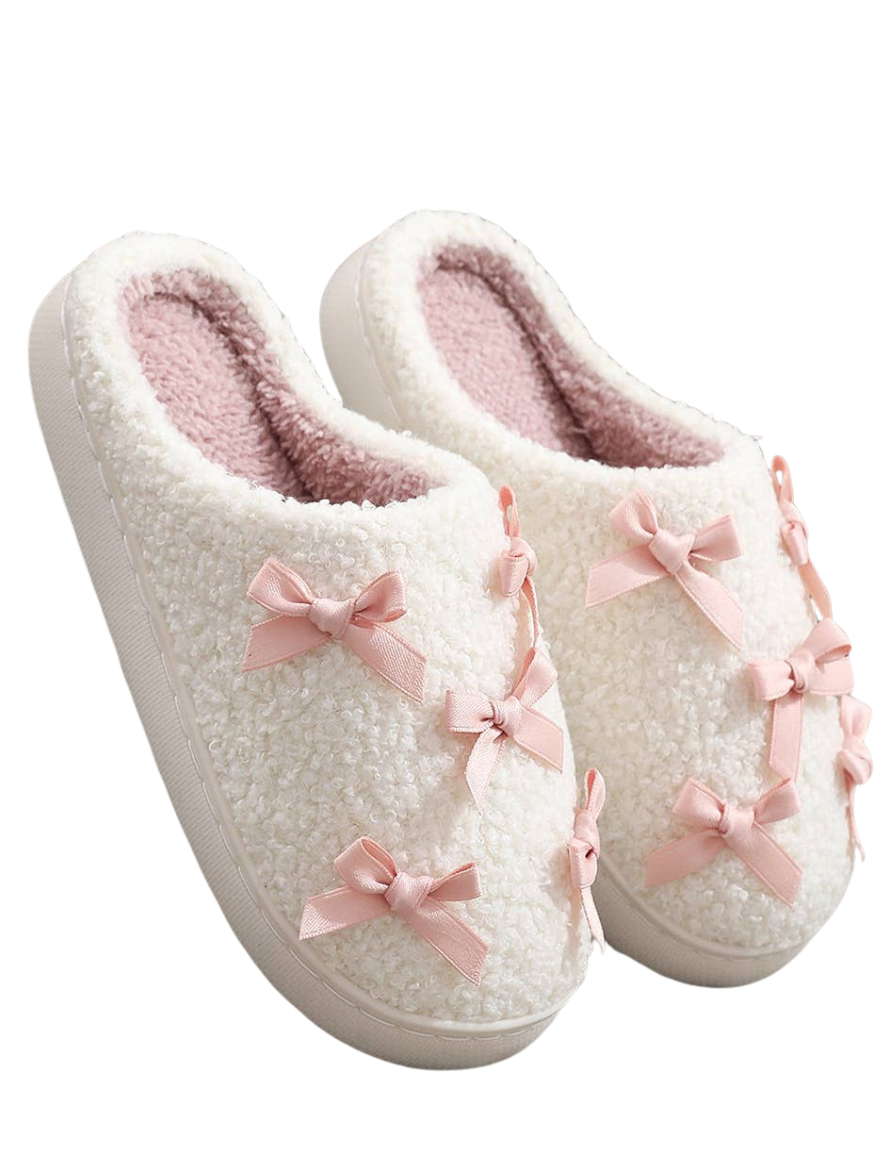 Pair of white slippers with pink bows on a white background