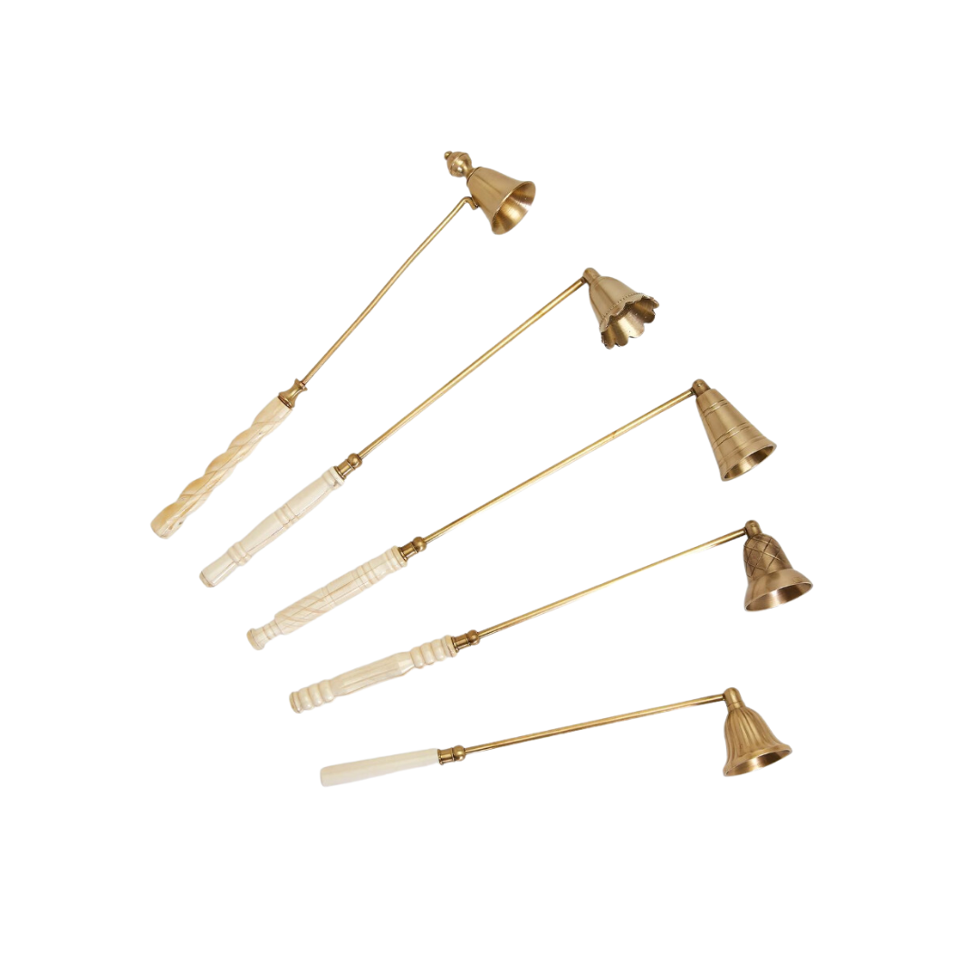 A collection of brass bell-shaped candle snuffers with antiqued gold finish and white handles.