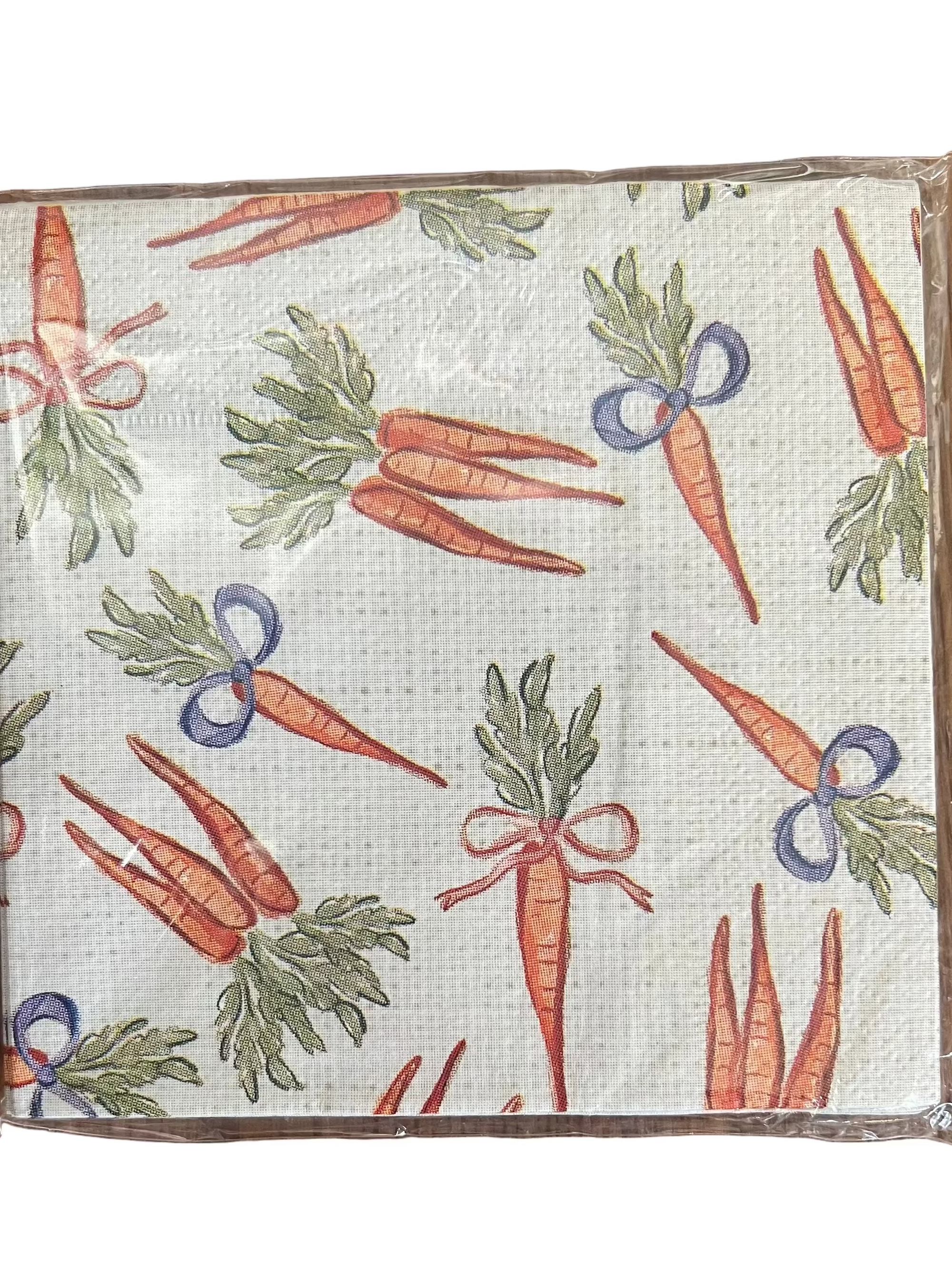 A square fabric napkin with a brown border, featuring a repeating pattern of illustrated carrots in orange with green leafy tops and small blue ribbon accents, on a white background.