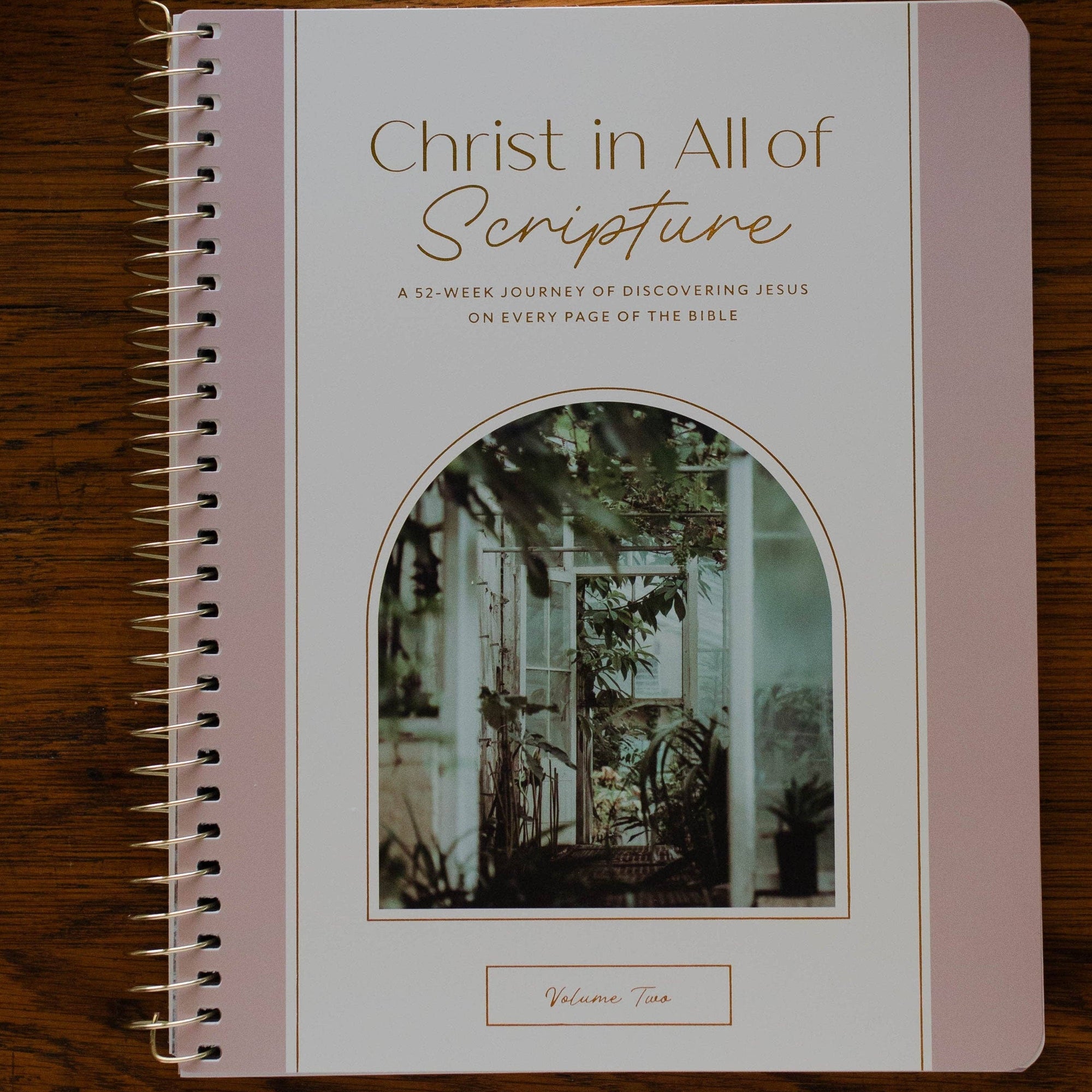 Notebook titled 'Christ in All of Scripture' on a wooden surface with a cup and glasses.