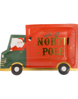 A festive paper plate shaped like a North Pole delivery truck, featuring a red side with gold 'NORTH POLE DELIVERY CO' lettering, a green cab, and an illustration of Santa waving from inside.