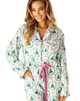 Woman wearing a festive pajama set in a room decorated for Christmas.