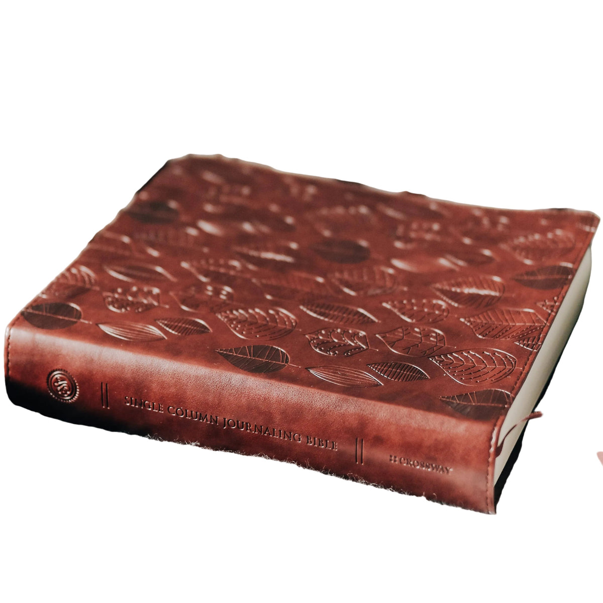 Brown leather-bound book with embossed design on a plaid fabric background
