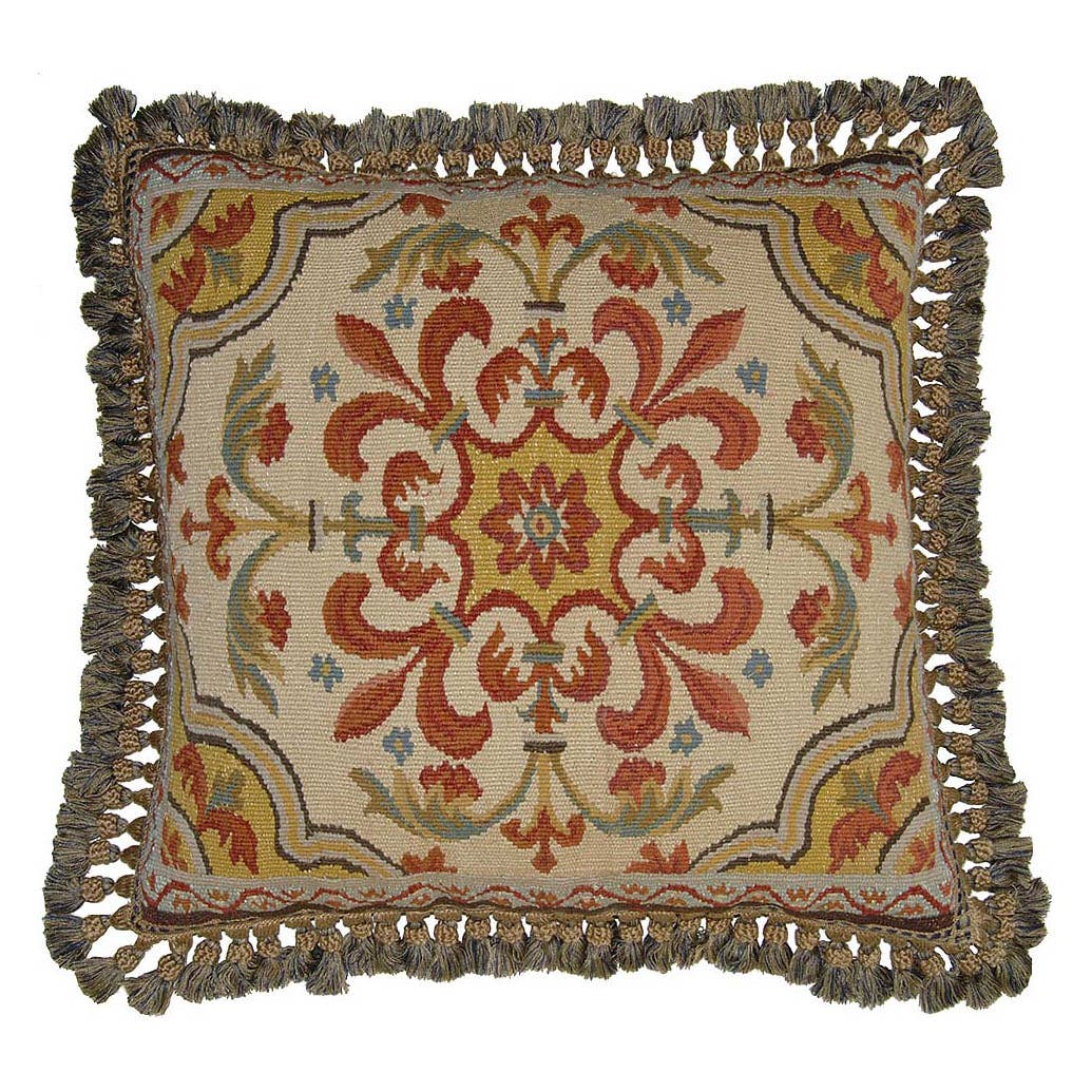 A square decorative throw pillow with a woven floral medallion pattern in rust red, mustard yellow, and sage green on a cream background, finished with a thick fringed border.