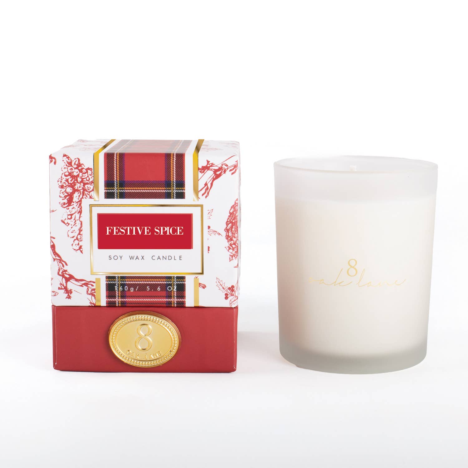 A 'Festive Spice' soy wax candle shown next to its retail packaging box. The candle is in a frosted glass jar with gold branding, and the box features a red and white plaid pattern with red floral accents and a gold seal.