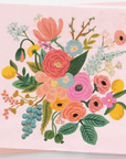 A stack of light pink paper napkins featuring a colorful floral illustration with pink, orange, yellow, blue, and green flowers and leaves on a white background.