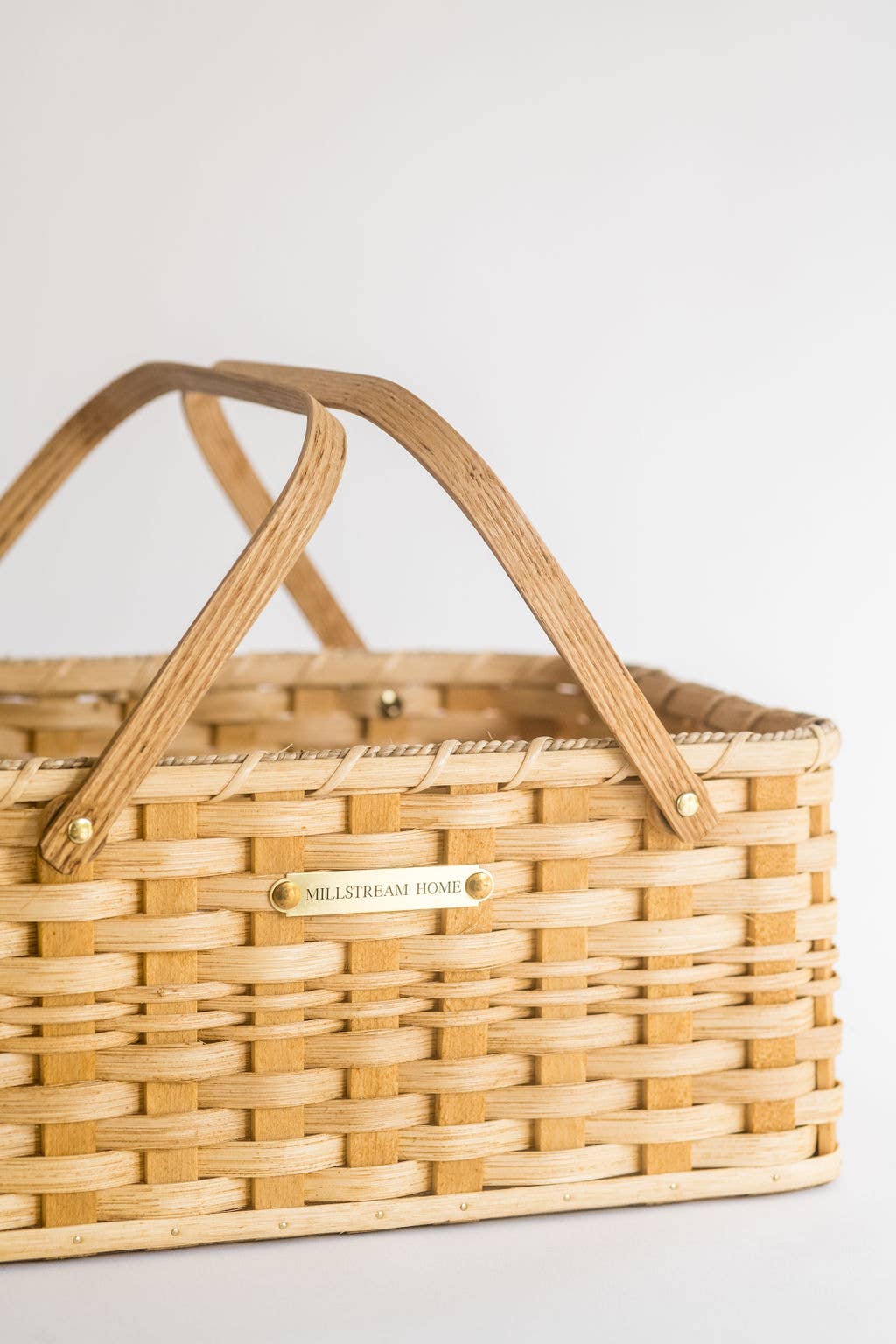 Woven picnic basket with wooden handle on a light background
