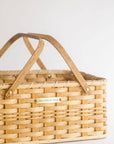 Woven picnic basket with wooden handle on a light background
