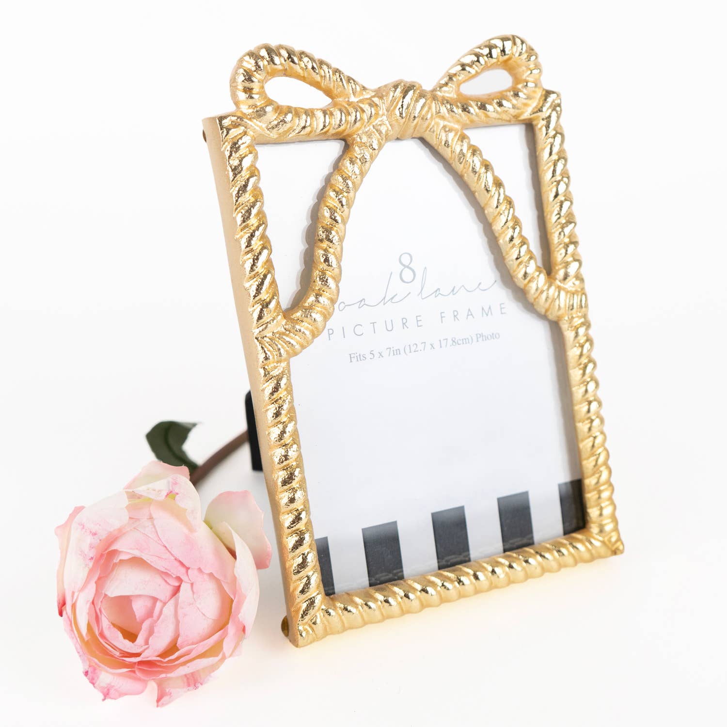Gold bow-shaped picture frame with a pink rose on a white background
