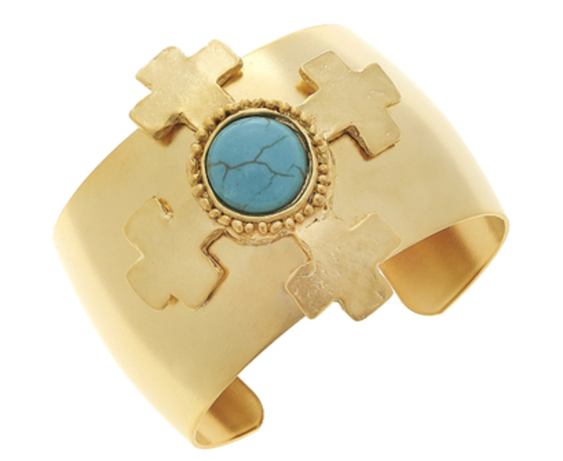 A gold cuff bracelet with handcast crosses and a central turquoise stone, with crosses.