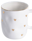 A white porcelain mug with gold-tone heart decorations