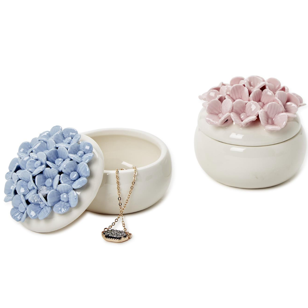 Two hand-painted porcelain jewelry boxes, one in blue and the other in pink, each with a floral design resembling hydrangea blooms on top.