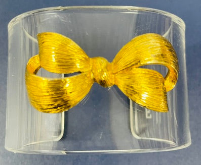 Clear cuff bracelet with a gold bow on a blue background