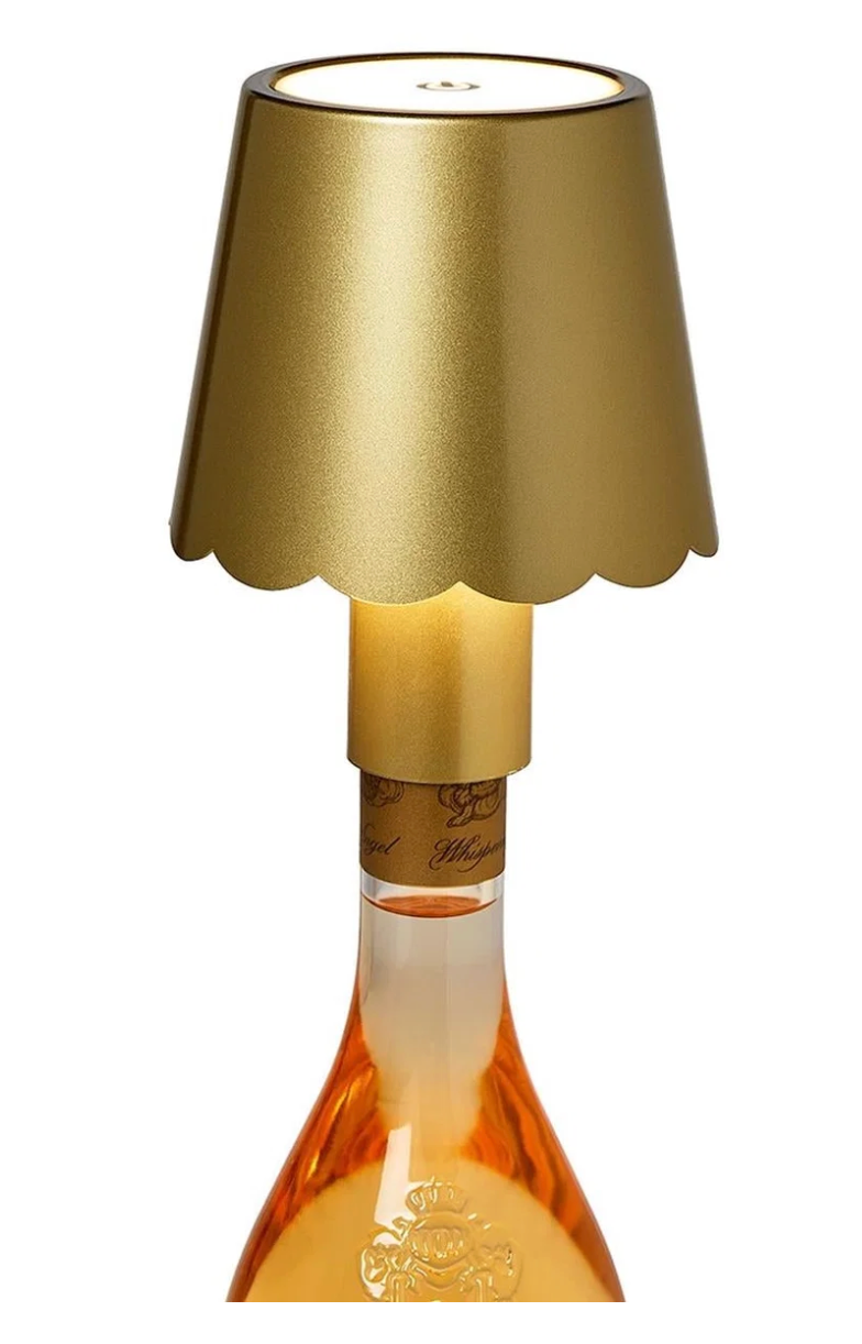 A champagne bottle lamp featuring a metallic gold scalloped shade, a gold neck collar, and a clear glass bottle filled with champagne-colored liquid, shown against a solid white background.