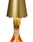 A champagne bottle lamp featuring a metallic gold scalloped shade, a gold neck collar, and a clear glass bottle filled with champagne-colored liquid, shown against a solid white background.