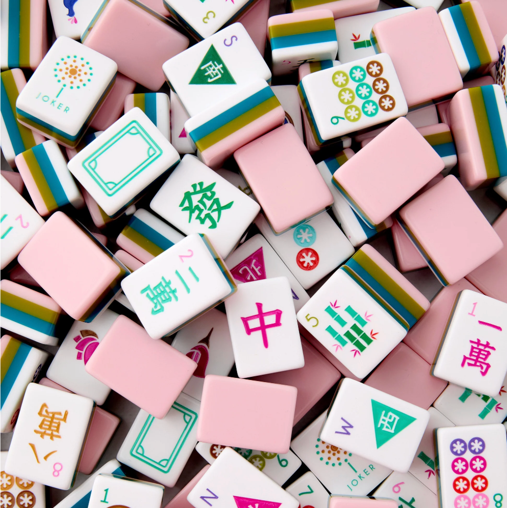 A pile of pink and white Mahjong tiles with colorful Chinese characters and symbols, filling the entire frame.