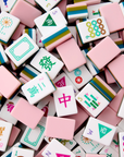 A pile of pink and white Mahjong tiles with colorful Chinese characters and symbols, filling the entire frame.
