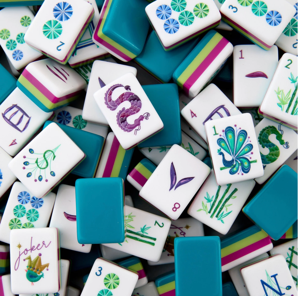 A close-up pile of Mahjong tiles showing various symbols, numbers, and colors including teal, white, pink, green, and purple.