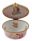A hand painted porcelain Limoges box with floral patterns and gold accents, depicting a child on the lid.