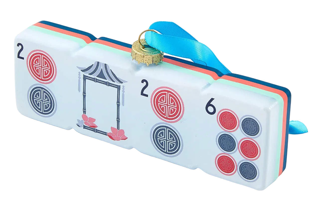 A decorative gift box designed to look like a Mahjong tile, featuring a white face with red and blue circular symbols, a black-and-white frame illustration, and a blue hanging ribbon with a gold ring.