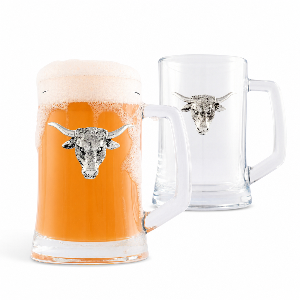 Two clear glass beer steins with white handles and a silver bull head emblem on the front, shown on a white background. The front stein is filled with orange beer and foam, while the rear stein is empty.