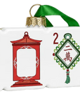 A decorative Christmas ornament shaped like a row of Mahjong tiles, featuring a green hanging ribbon at the top, white tile faces with red and green Chinese-style decorative motifs, and a red temple ornament in the center.