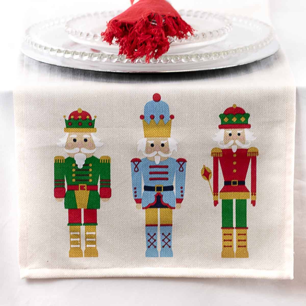 Decorative table runner with embroidered nutcracker designs on a white background
