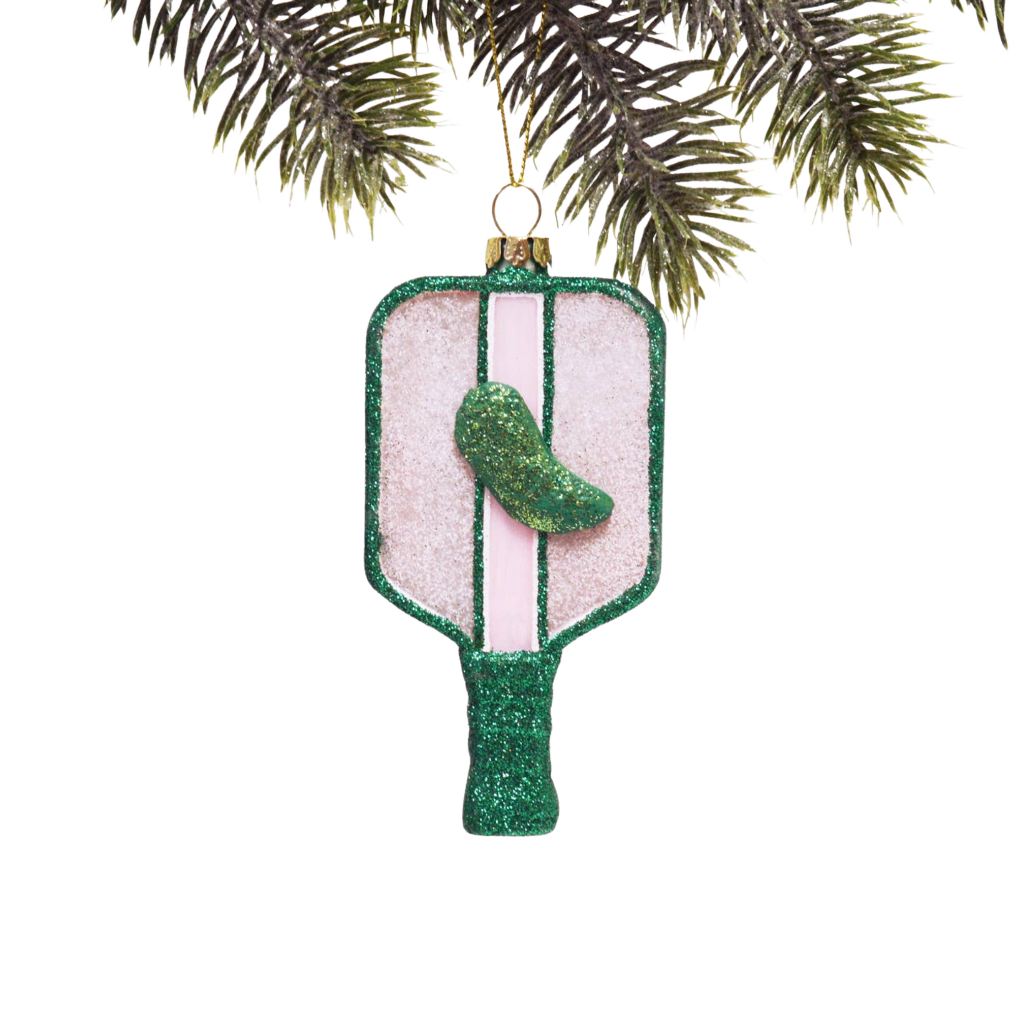 Decorative ornament shaped like a pickle on a green glittery base, hanging from a tree branch.