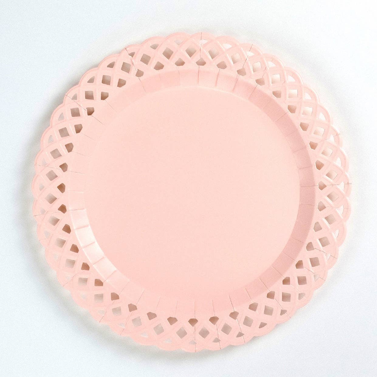Pink paper plate with lace-like edge on a light gray background