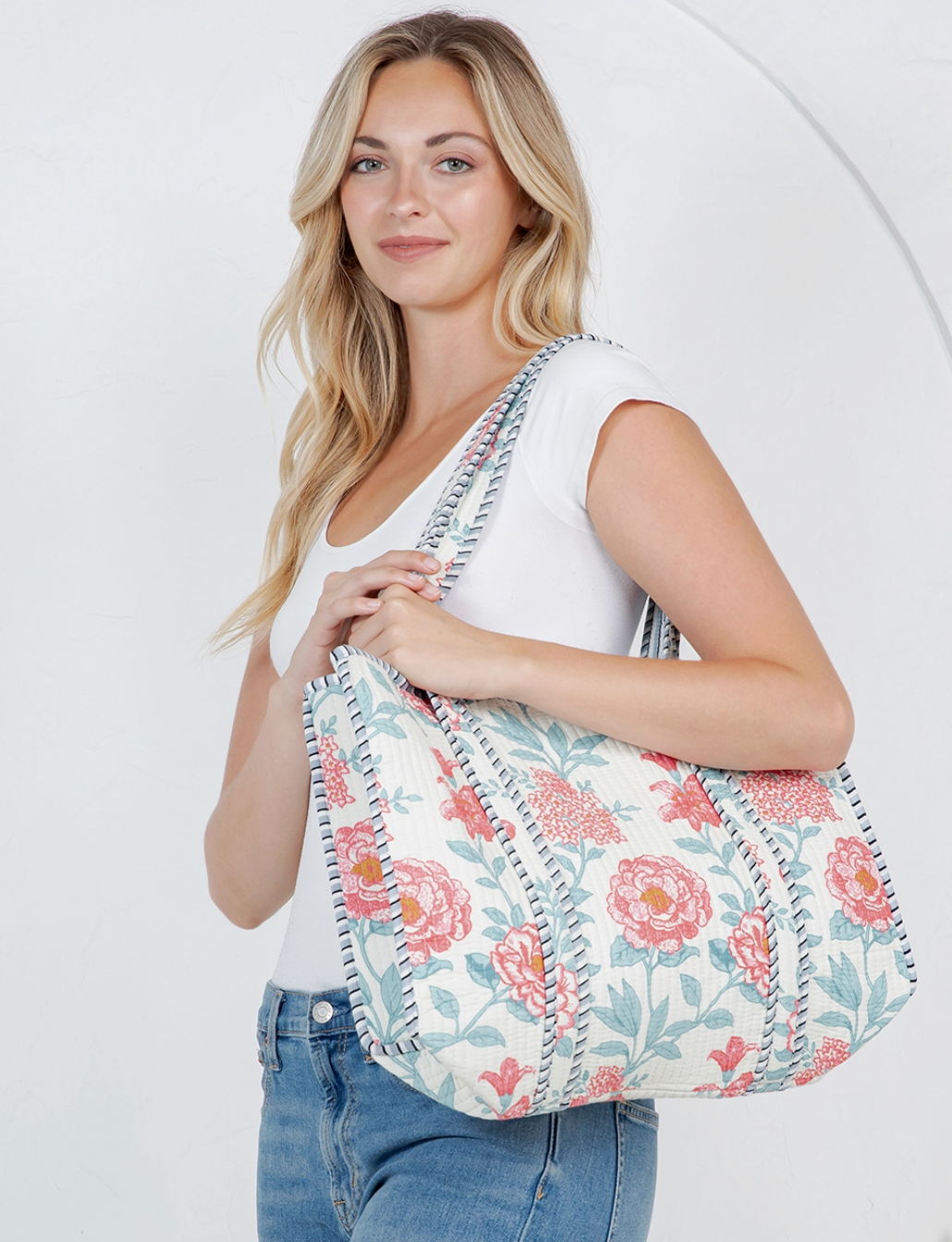 Woman holding a floral-patterned bag against a white background